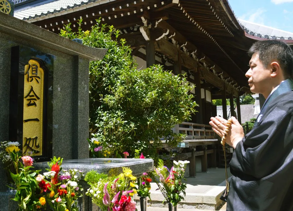 岡崎市の本光寺の住職が永代供養墓「倶会一処」に手を合わせて供養しています